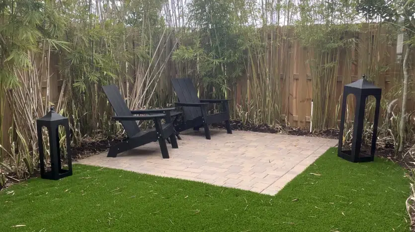 Jardín de casa con dos asientos y césped sintético